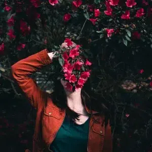 Une femme se cache derrière des fleurs